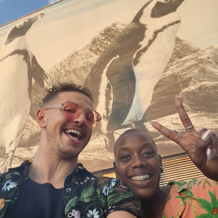 Julian and Imani laughing together in front of a large penguin mural.